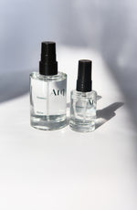 Two glass bottles of Arq Botanics Detox Cucumber Hyaluronic Facial Mist. The larger bottle has a pump dispenser, and the smaller one has a spray nozzle. Both are resting on a white surface.