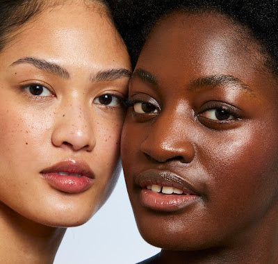 A photograph of two women with contrasting skin tones, standing side by side and radiating joy and camaraderie.